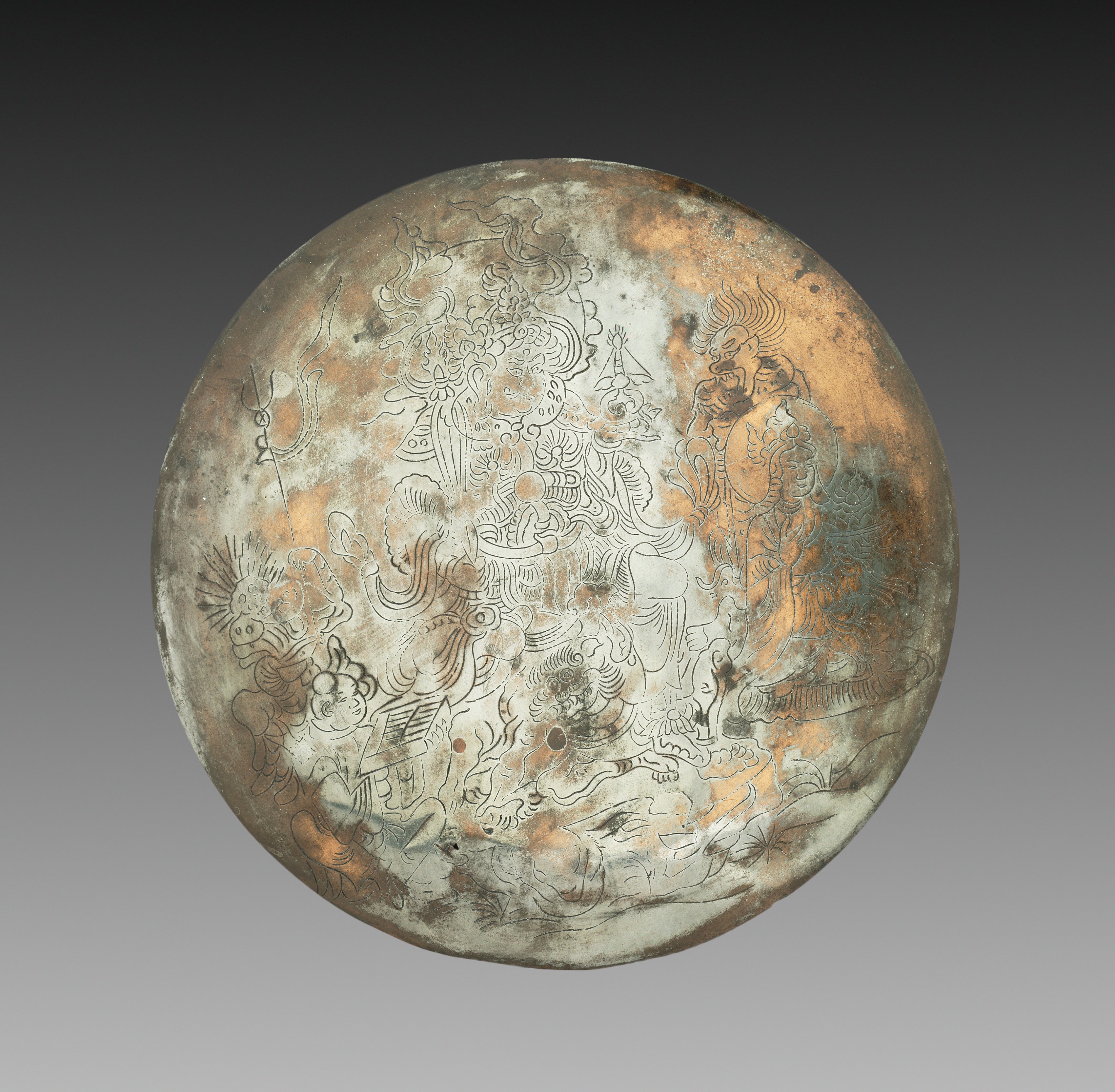 Circular bronze mirror, its silvered face line-engraved with Bishamonten standing in armour with halberd and stupa, an attendant entourage around him, and a small demon crouched