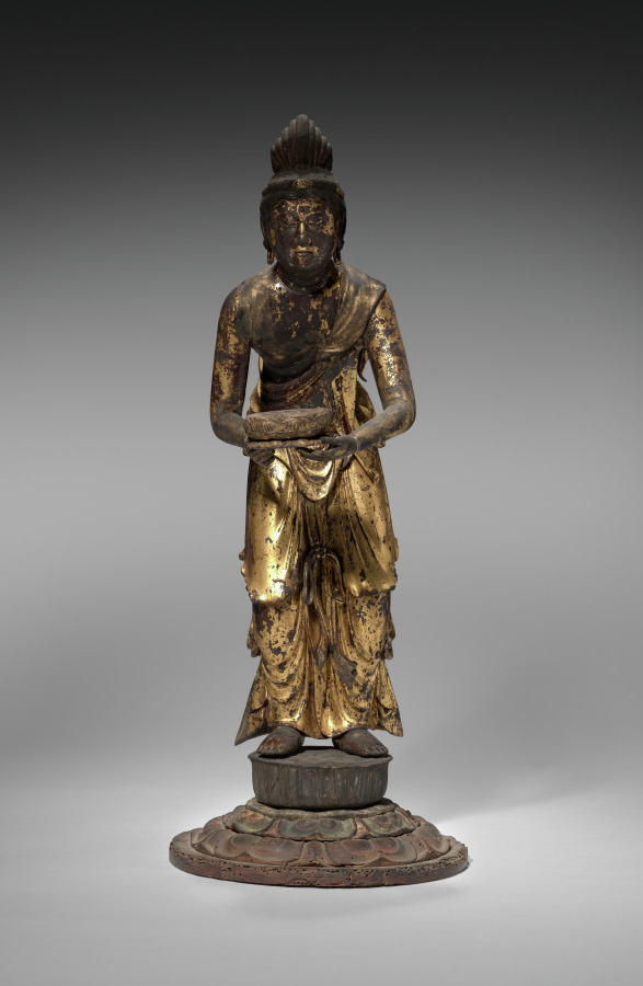 Kamakura standing wood Kannon with lacquer and gold leaf, early 1200s, 59 cm. The figure holds a wide three-tiered lotus dais at chest height; head inclined.