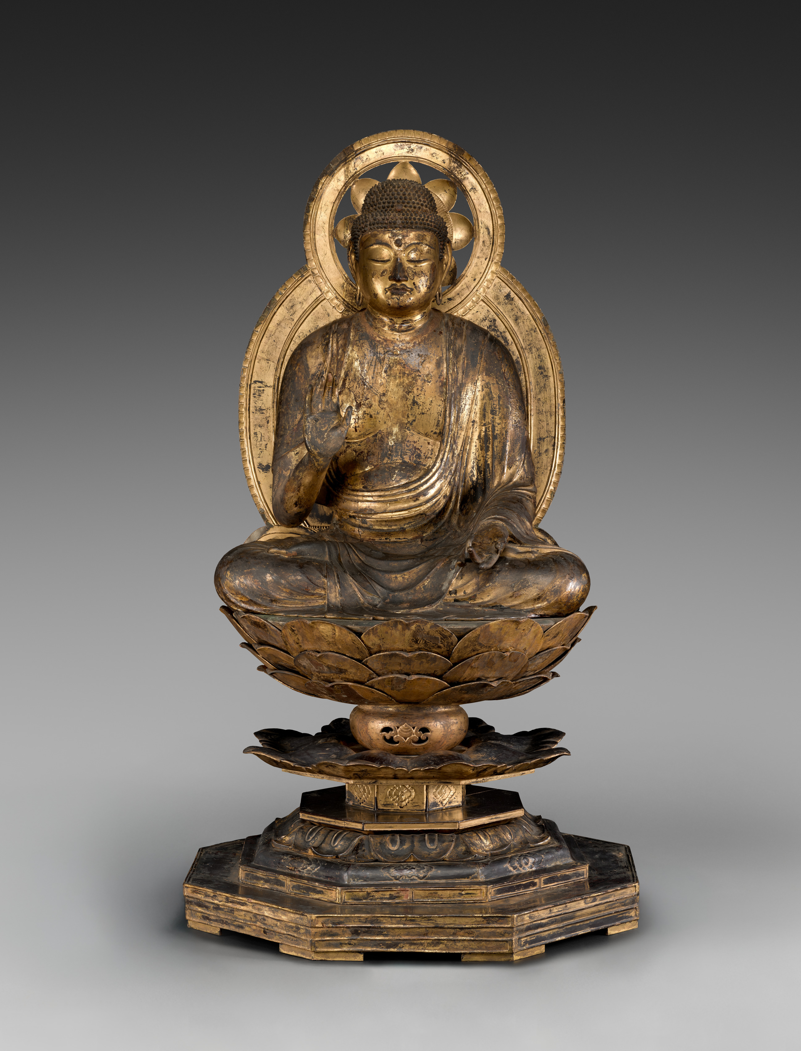 Late-Heian seated Buddha in gilded yosegi wood, 1100s, 145 cm on a lotus pedestal. Right hand in abhaya mudrā; left hand a later replacement, gesture lost.