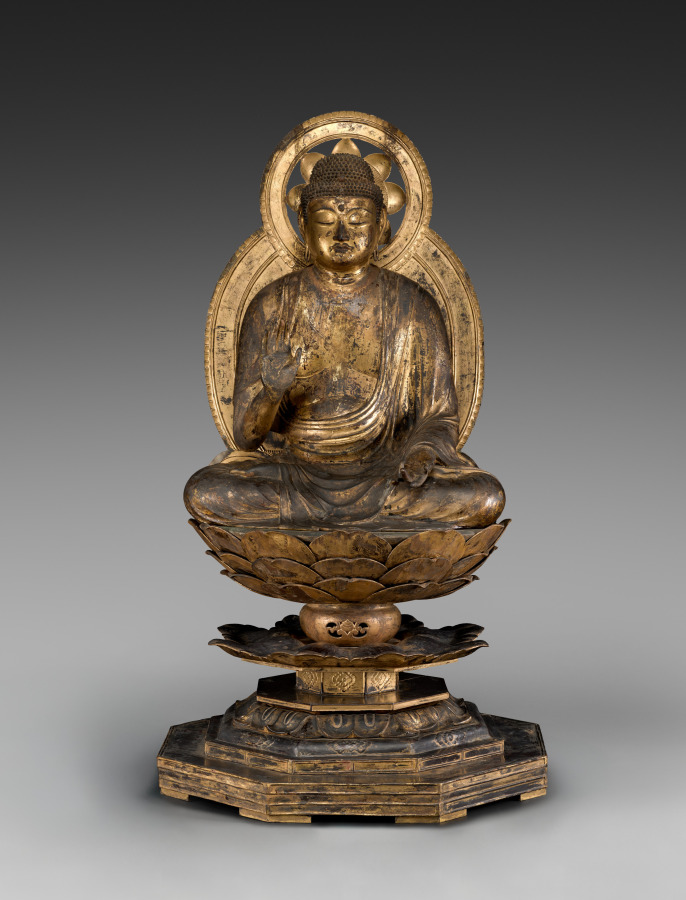 Heian 12th-c. seated gilded-wood Buddha in full lotus on a tiered lotus throne. Right hand in abhaya mudrā; left hand a 20th-c. replacement, gesture lost.