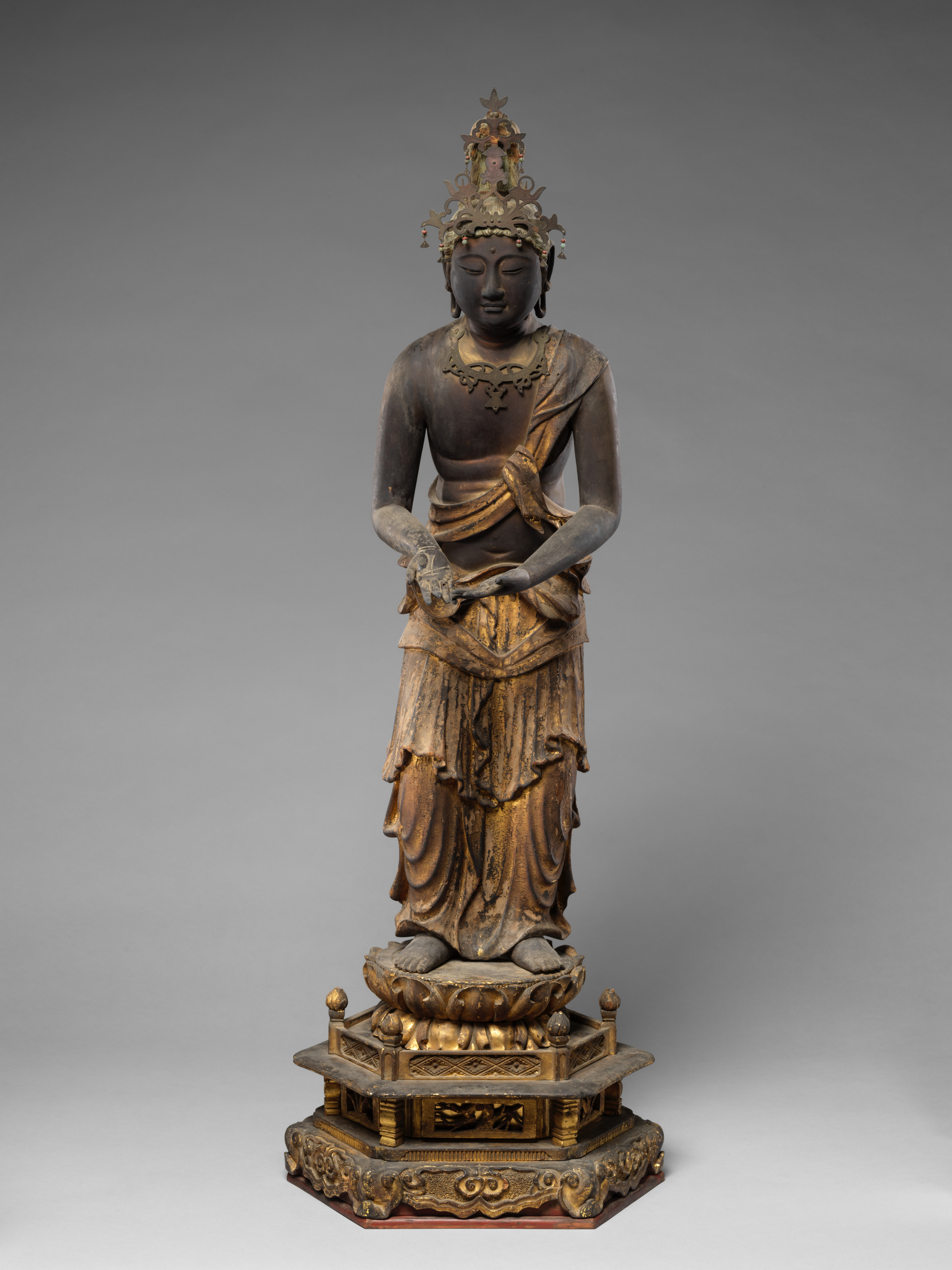 Kamakura attendant Kannon in painted-and-gilt wood with gyokugan eyes, late 12th–13th c., 84 cm. Raigō contrapposto; lotus stem at left hand; tall crown.