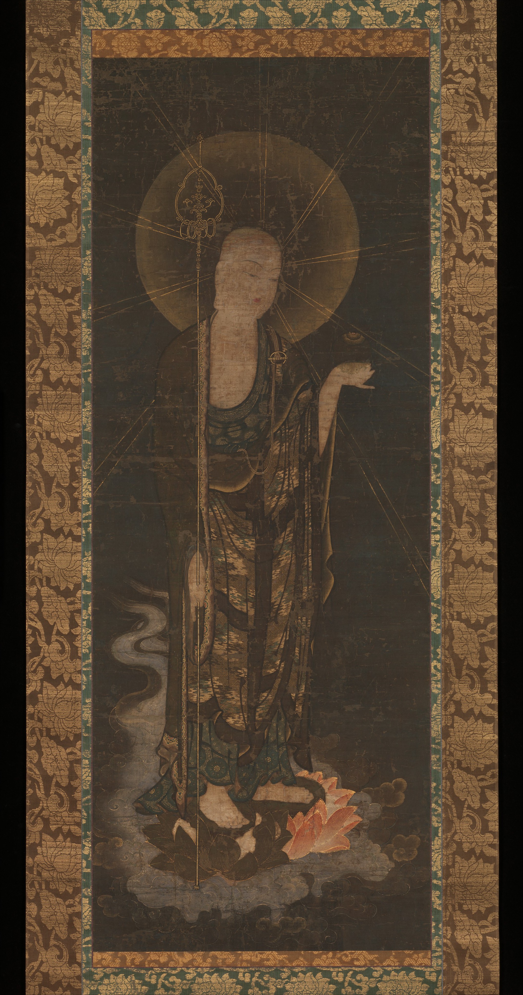 Kamakura c. 1300–33 hanging scroll, colour gold and kirikane on silk, 107 × 40 cm. Monk-form Jizō descends on a lotus amid spiral clouds; shakujō right, hōju left.