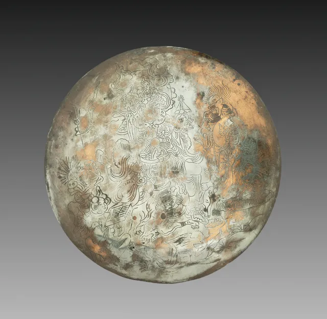 Circular bronze mirror, its silvered face line-engraved with Bishamonten standing in armour with halberd and stupa, an attendant entourage around him, and a small demon crouched