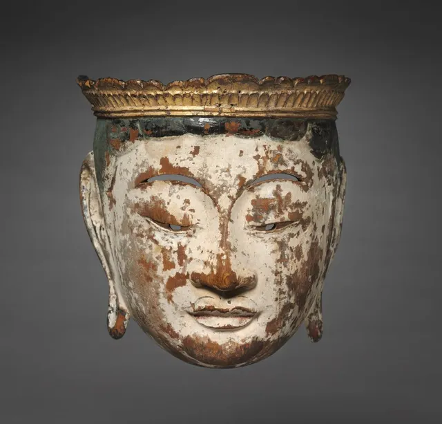 Late-Heian processional bodhisattva face-mask, lacquered painted wood, late 1100s, 22 × 16 cm. Worn white paint, narrow eye-slits, gold petaled crown.