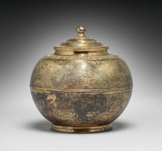 Heian gilt-bronze covered cinerary urn, 800s–900s, 26 cm. Pomegranate-bud finial on a stepped lid; chased petal-band; faint Pure Land engraving above.