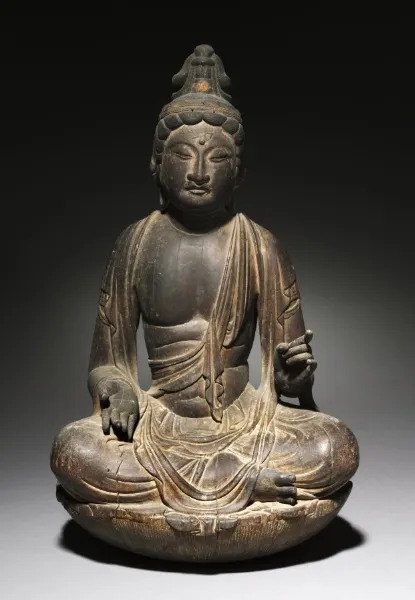 Heian c. 800 seated Nikkō Bosatsu in kaya wood, 47 cm. Single-block, weathered surface. Proper-left hand raised at chest for the now-lost sun-disc attribute.
