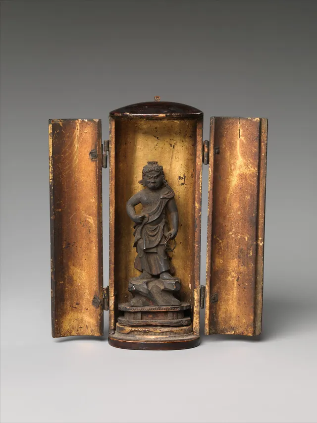 Open hinged miniature lacquer shrine, gold interior, holding a standing Fudō Myōō figure under 4 cm tall — sword right, lasso left, against a small carved flame mandorla.