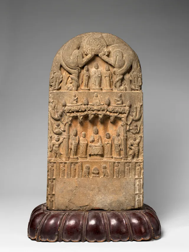 Round-topped limestone stele on a lobed wooden stand: a small triad in the arched lunette; below, Amitābha enthroned under a tasselled canopy with standing flanking bodhisattvas