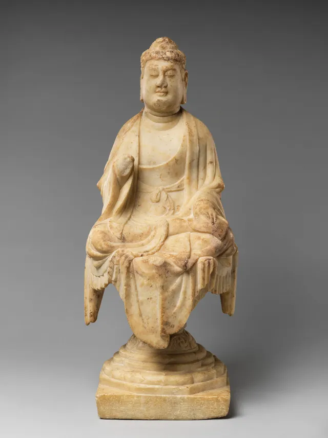 Tang Chinese marble Buddha dated 707, seated with one knee raised, drapery in heavy modelled folds over a stepped throne, rounded fleshy face, weight readable through the cloth.